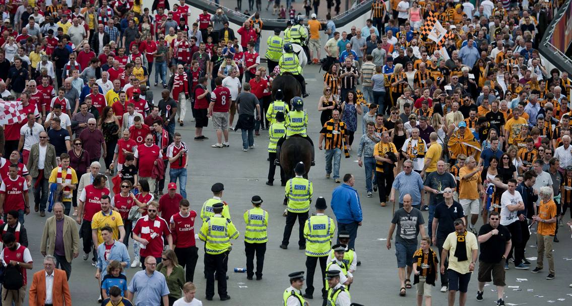 Poliziotti disarmati tra i tifosi di Arsenal e Hull City che si apprestano ad entrare pacificamente allo stadio. Afp